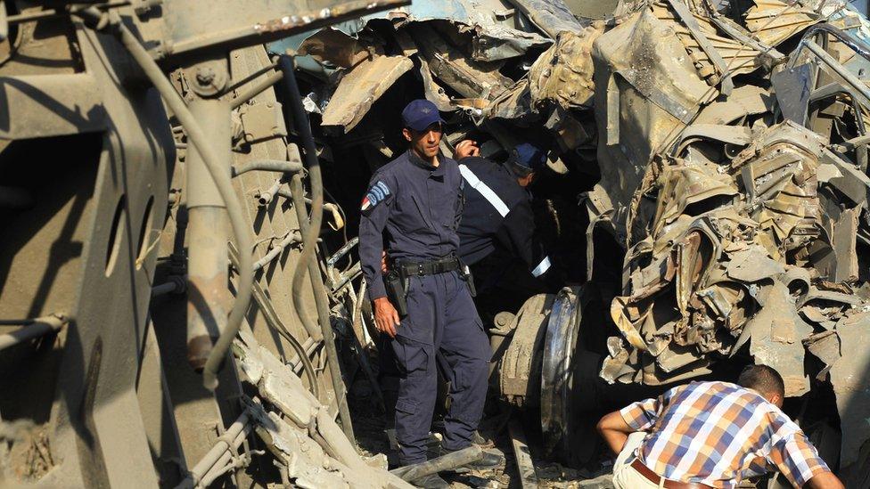 Egyptian security personnel examine wreckage after two passenger trains collided in Alexandria