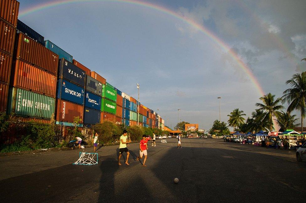 Boys play football underneath a rainbow