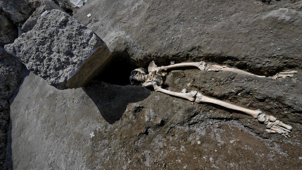 The skeleton of a victim of the eruption that destroyed Pompeii, shown with a huge boulder where his head should be