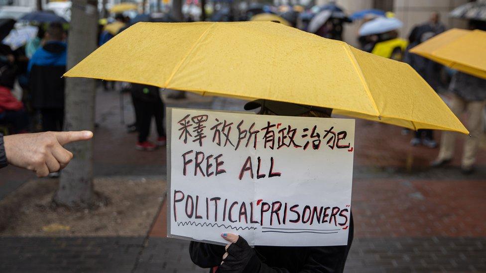 A supporter of democracy activists holds a placard while standing outside the West Kowloon court building in Hong Kong, China, 04 March 2021. A bail hearing for 47 pro-democracy figures charged with subversion has entered its fourth day. EPA/JEROME FAVRE