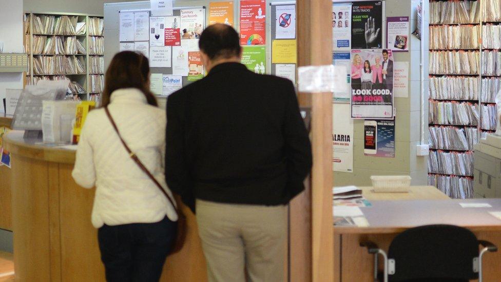 A man and a woman at a GP surgery reception