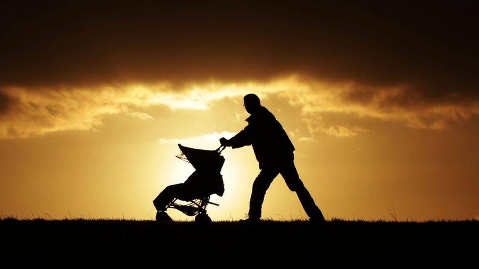 A man pushing a baby buggy during sunset on Parliament Hill