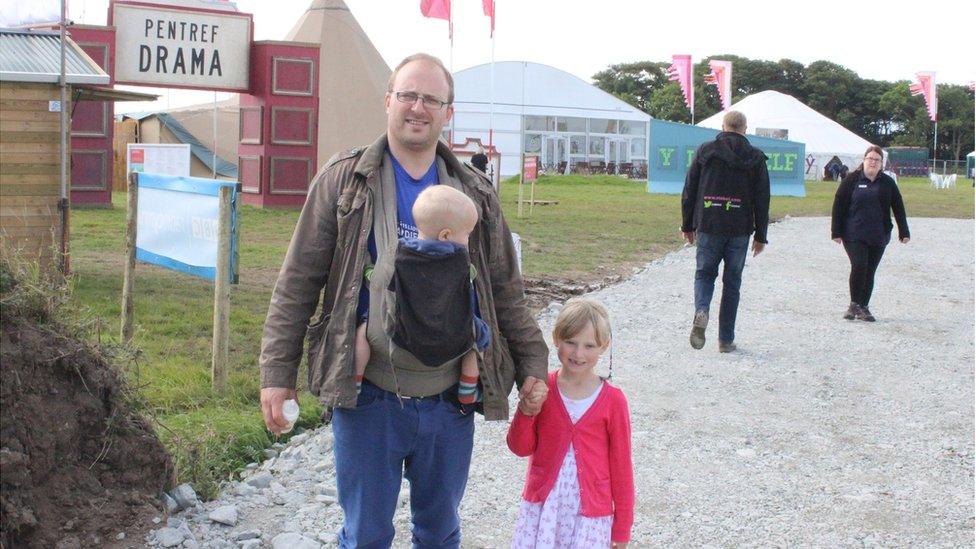 Aneirin Karadog yn cael hoe o farddoni am eiliad er mwyn mynd am dro o gwmpas y Maes gyda'i ferch fach Sisial a'i fab ErwanTeifi // Last year'swinner of the Eisteddfod chair, Aneirin karadog, takes a break from poetry to check out the Maes with his family