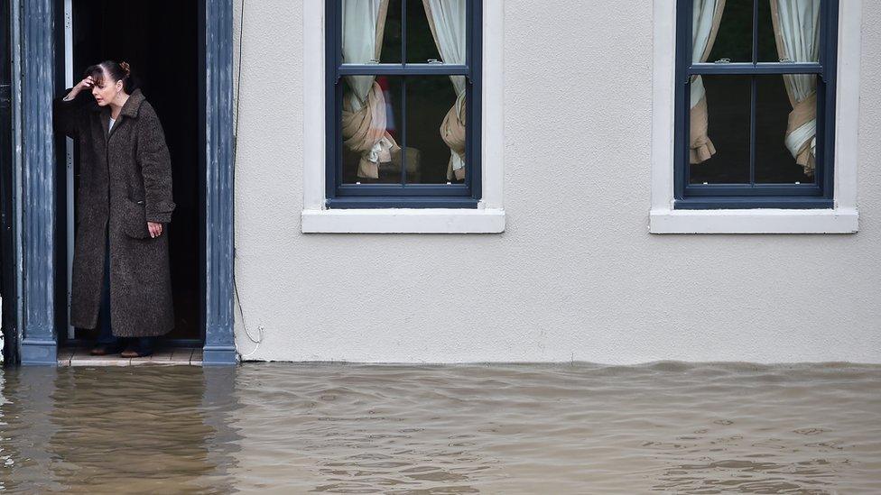 A resident watches flood waters outside her house