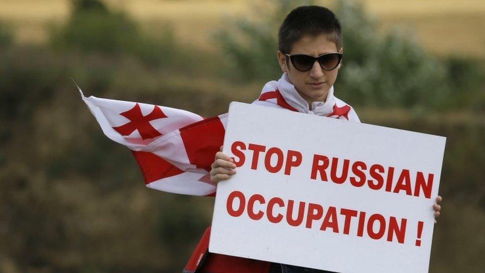 A Georgian protester holds a placard reading "Stop Russian Occupation" during an anti-Russian rally near the border between Georgia and the breakaway region of South Ossetia, 14 July 2015