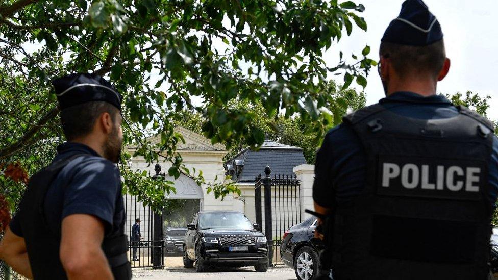 Police stand by as a convoy reportedly transporting Saudi Crown Prince Mohammed bin Salman leaves the gated entrance of the Chateau Louis XIV, in Louveciennes