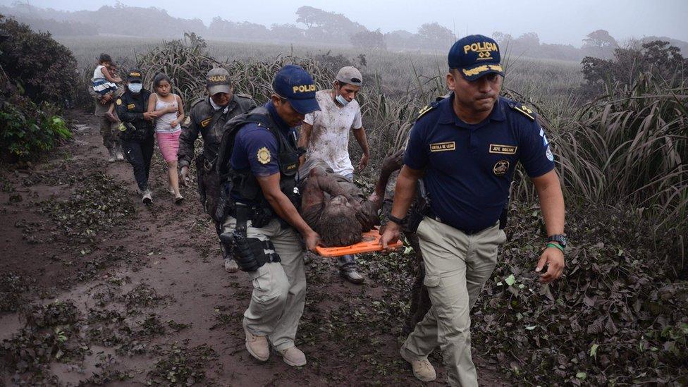 Police carry a wounded man in El Rodeo village