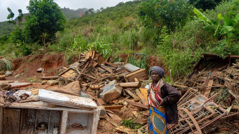 A woman stands next to her destroyed belongings on 19 March 2019, in Chimanimani, Zimbabwe