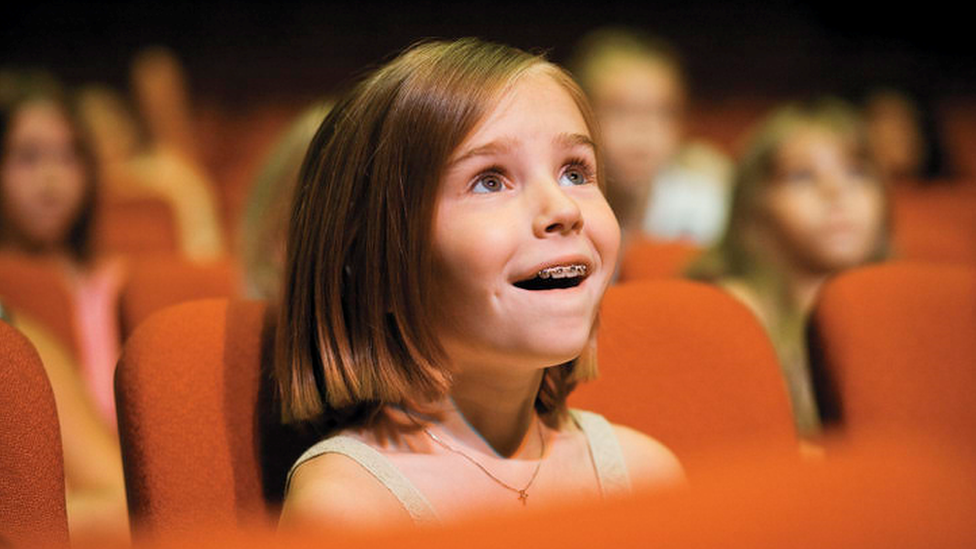 A young girl watches a film in the cinema