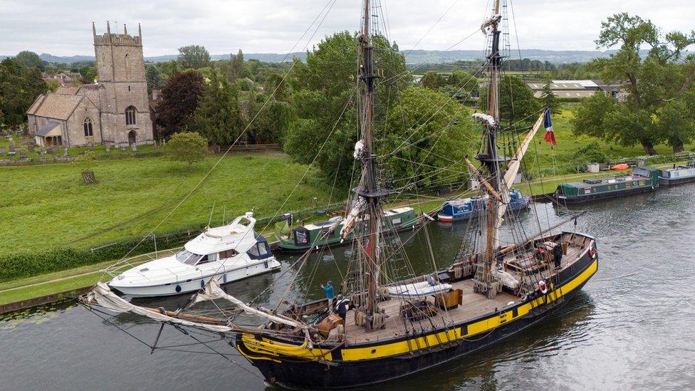 A tall ship sailing on a canal past a church