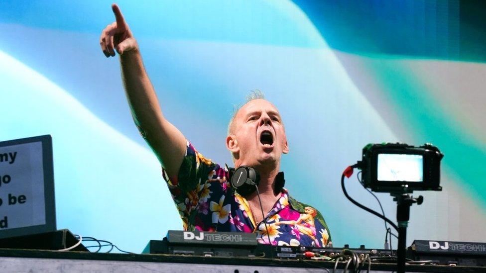 Fatboy Slim with his hand in the air as he headlines at Love Saves The Day