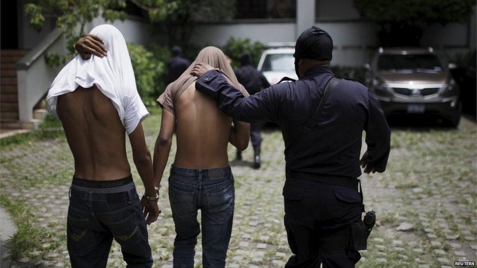 Suspected members of the 18th Street gang are guarded by a policeman in San Salvador on 29 July , 2015.