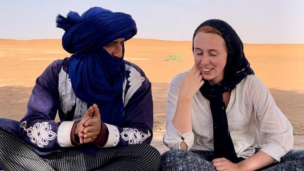 Ella Williams sits on rug in the desert