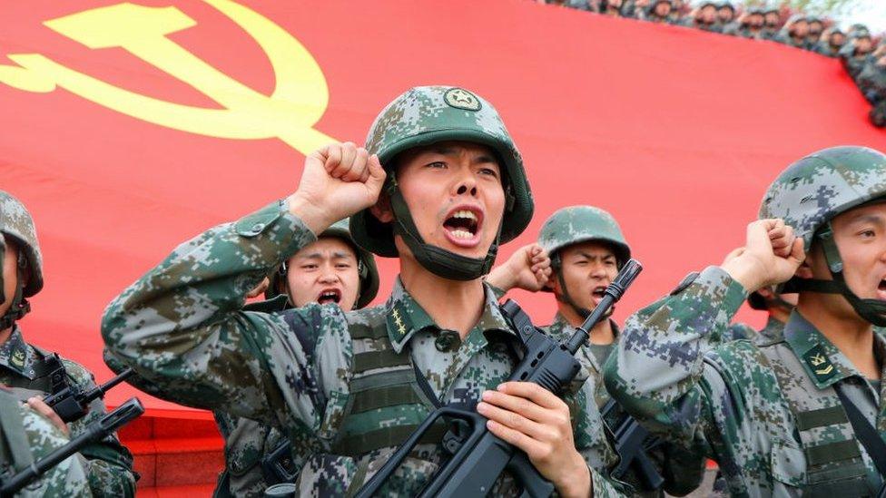 Chinese troops standing in front of a Chinese flag