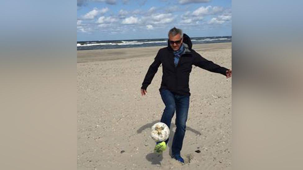 Thomas Selinger with the football on a beach