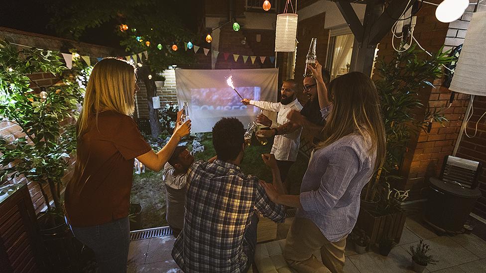 Football fans watching football on a projector screen in a garden