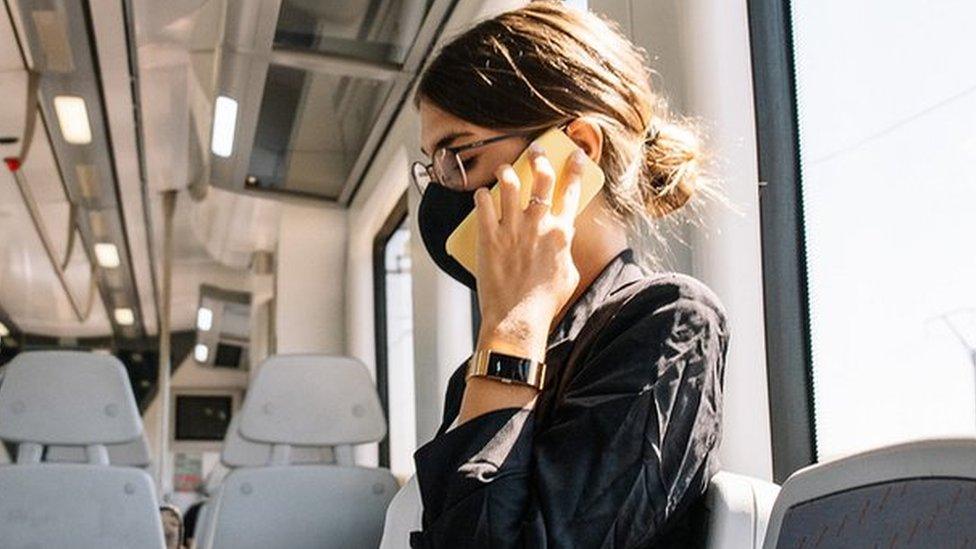 woman on empty train wearing face mask