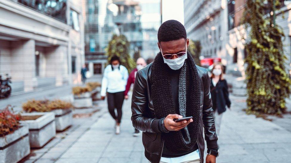 man wearing mask looking at phone