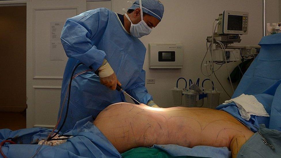 A surgeon performing butt enhancements