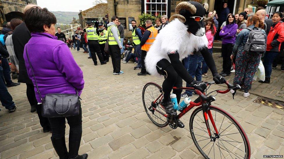 A cyclist dressed as a ram as the race passes through Haworth