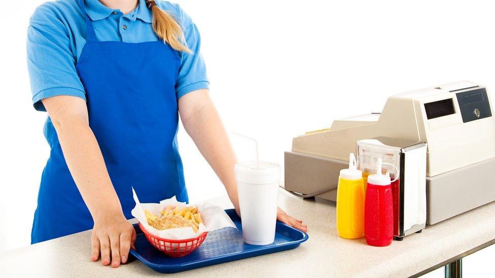 Teenage cashier serving fast food in a restaurant (posed image)