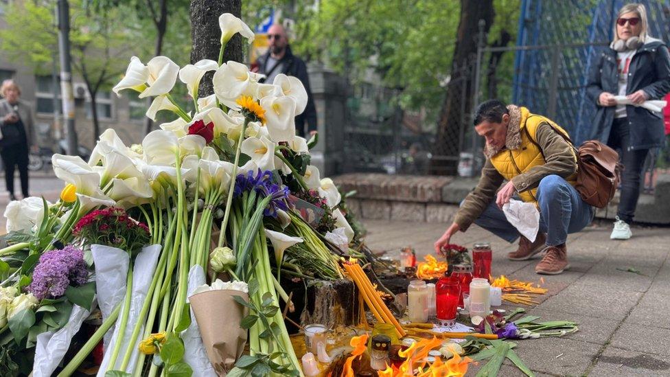 A man lights candles near a tribute to the children killed in Serbia