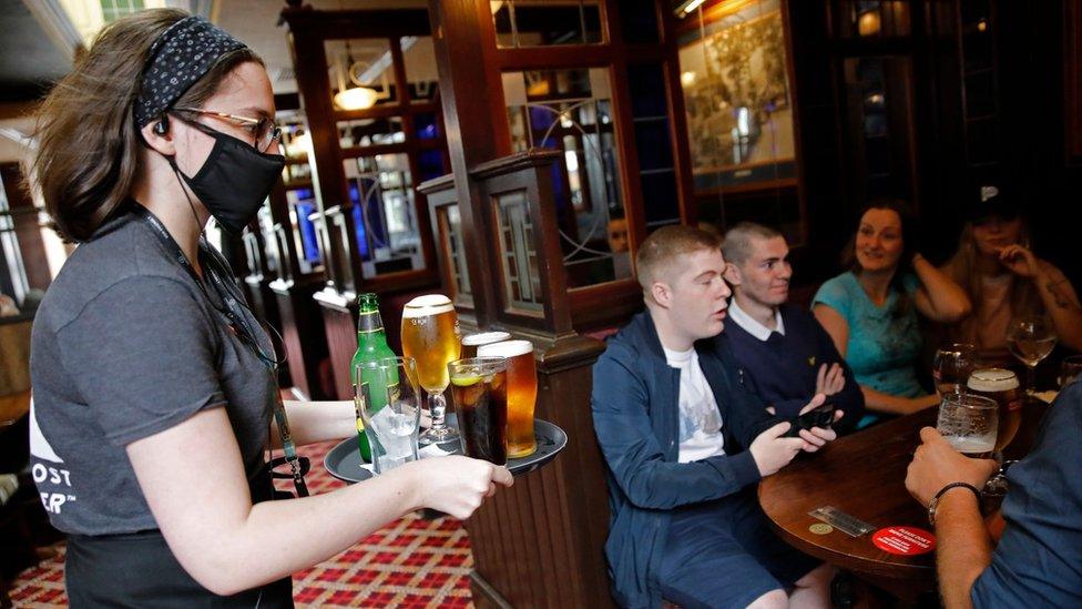 A bar worker serves customers at the Goldengrove pub in Stratford, east London