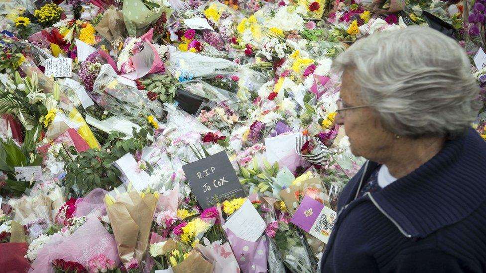 A woman looks at floral tributes in Birstall