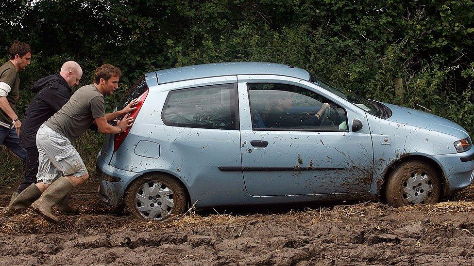 Men pushing a car at a festival