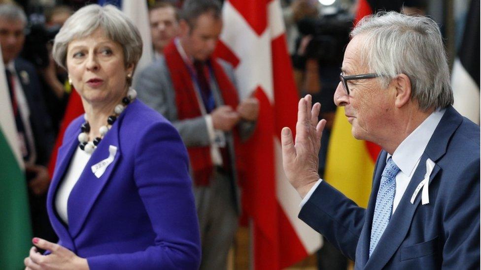 Jean-Claude Juncker waves at Theresa May at press conference