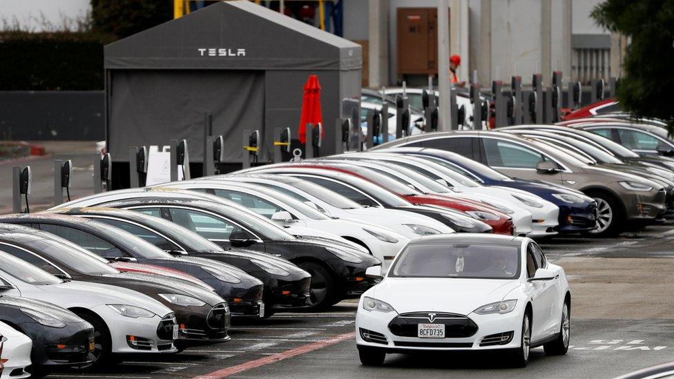 A Tesla Model S electric vehicle drives along a row of occupied superchargers at Tesla"s primary vehicle factory after CEO Elon Musk announced he was defying local officials" restrictions against the coronavirus disease (COVID-19) by reopening the plant in Fremont, California, U.S. May 12, 2020.