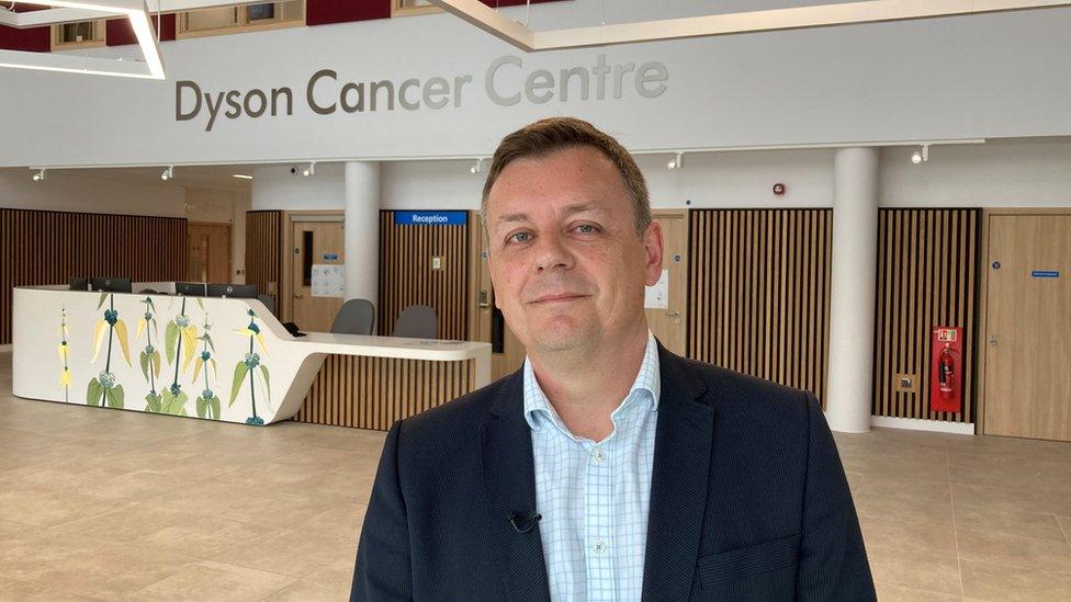 Mark Beresford photographed inside under a Dyson Cancer Centre sign