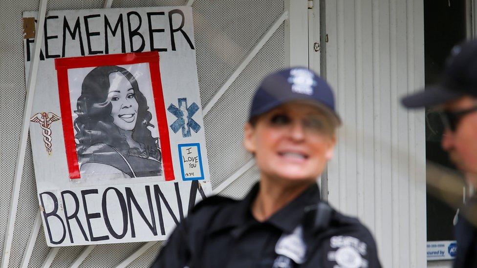 Officers stand near a sign depicting Breonna Taylor at a protest in in Seattle on 1 July 2020