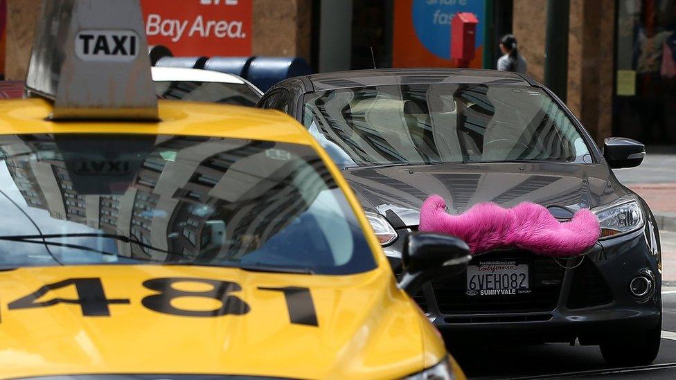 A Lyft car drives next to a taxi on June 12, 2014 in San Francisco, California.