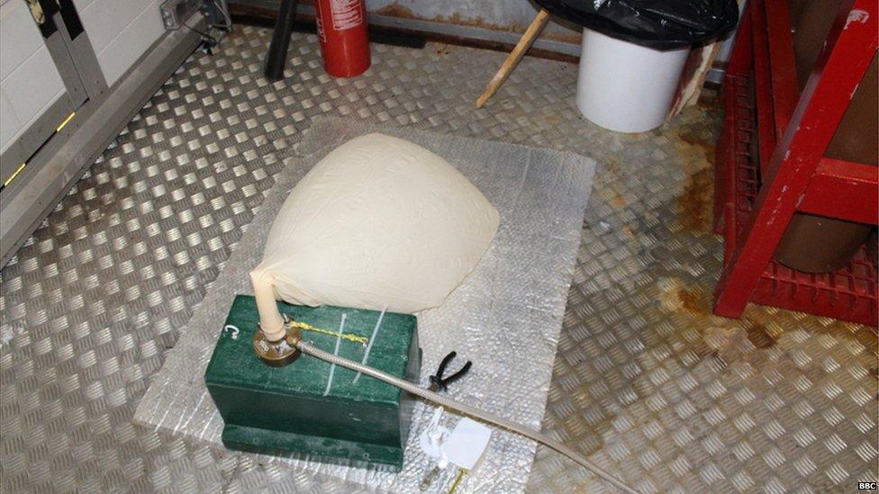 A white balloon attached to a helium nozzle on the ground