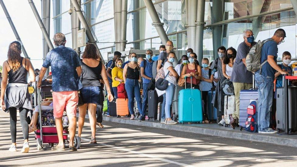 Holidaymakers standing in a queue at an airport