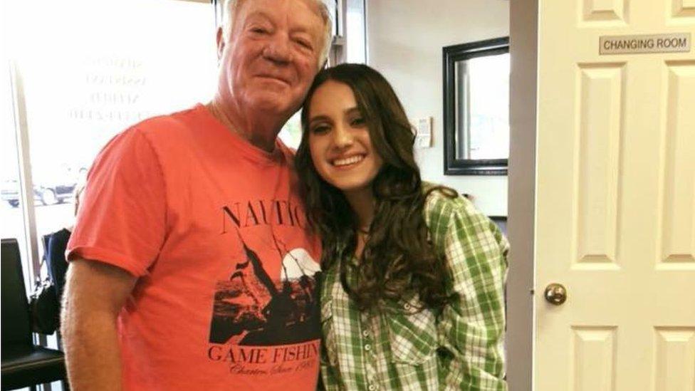 A teenage girl hugs an older man as they pose for a photograph