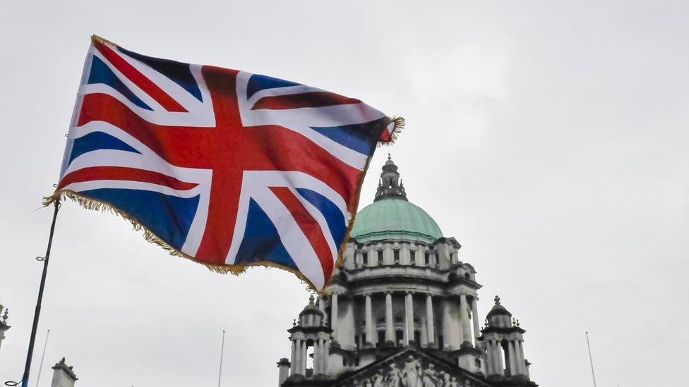 A union jack flies in front of Belfast City Hall