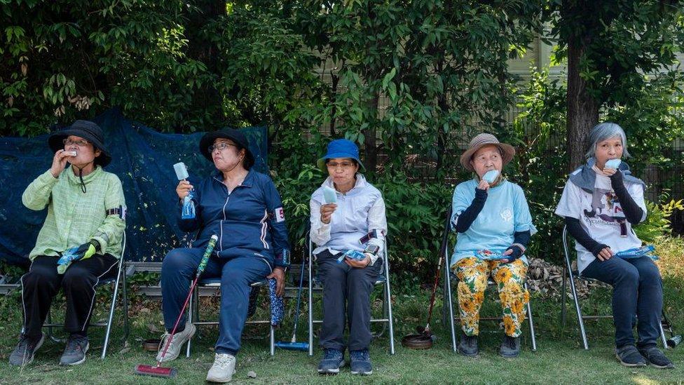 This photo taken on July 27, 2023 shows senior citizens enjoying cool popsicles after playing the croquet-inspired game of "gateball" at a park in suburban Tokyo