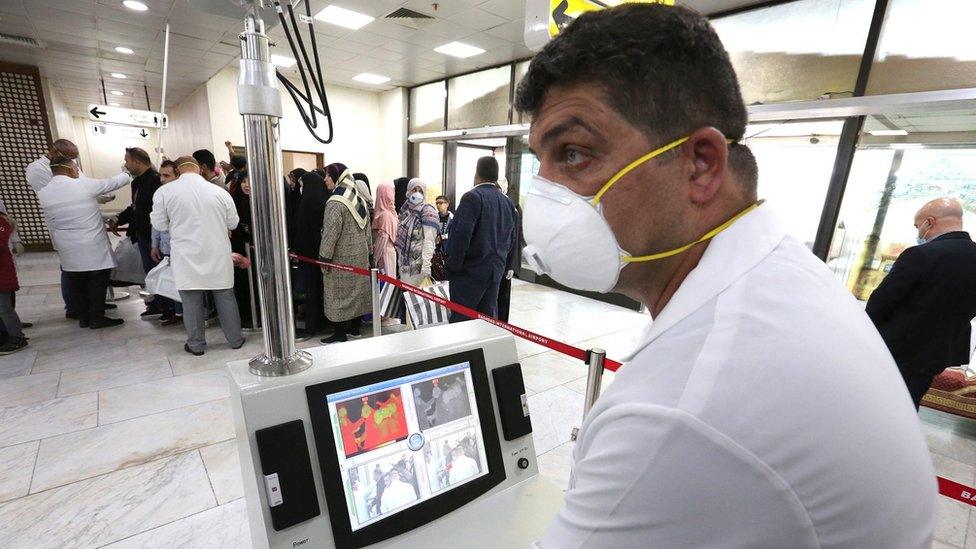 Members of Iraqi medical team check passengers upon arrival from Iran at Baghdad international airport