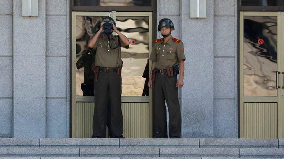 A North Korean soldier keeps watch toward the south through a binocular telescope at the truce village of Panmunjom, South Korea on 26 August