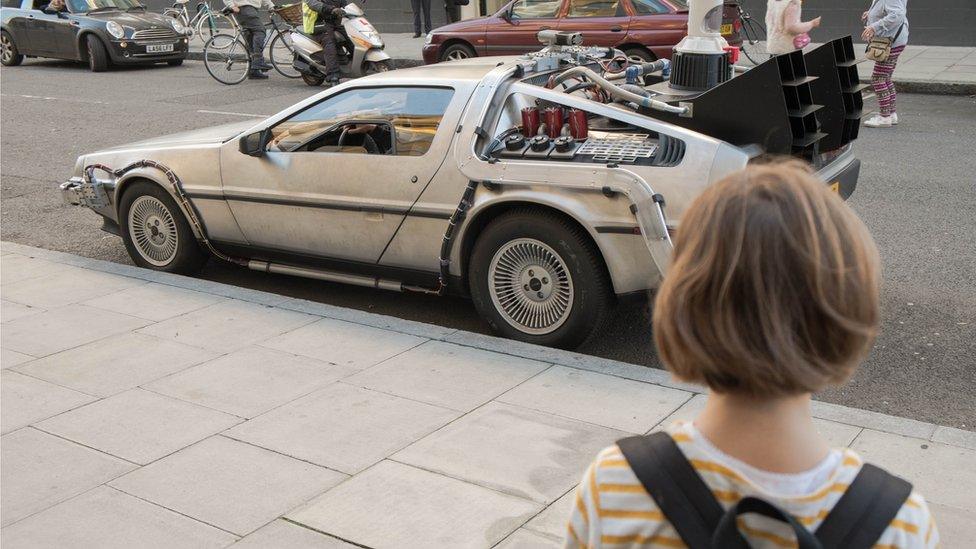 A little girl looks at the DeLorean vehicle