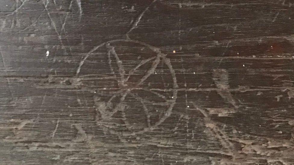 Carving on dark wooden beams of what appears to be "witches' marks"