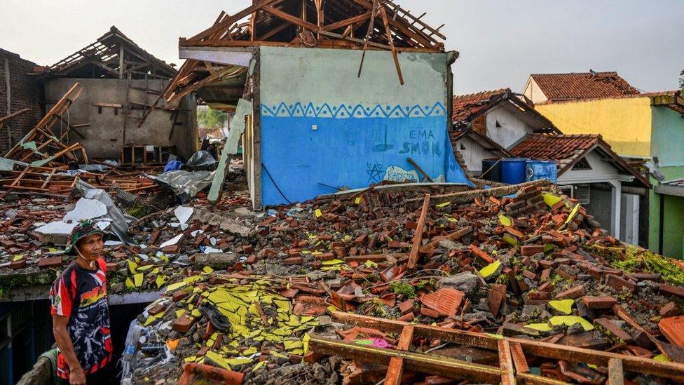 A man stands near damaged houses following a tornado at Sukadana village in Sumedang, West Java province