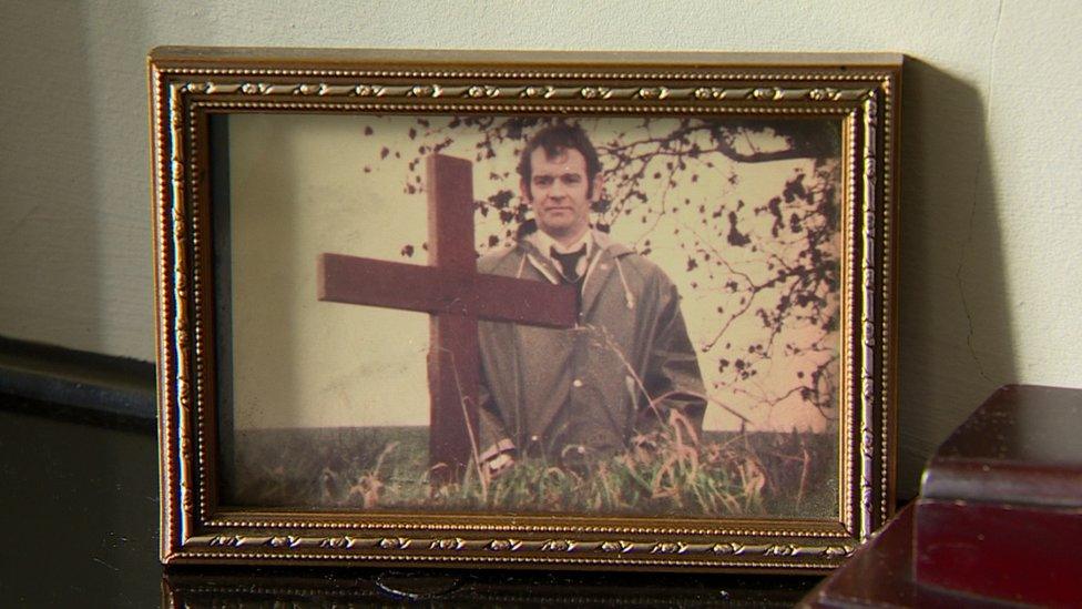 A photo of Alan Black at the site of the massacre in 1976 sits in his home