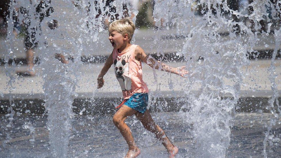 A little boy plays with water-jets in the fountain at the De Ferrari Square on a hot summer day, in Genoa, Italy