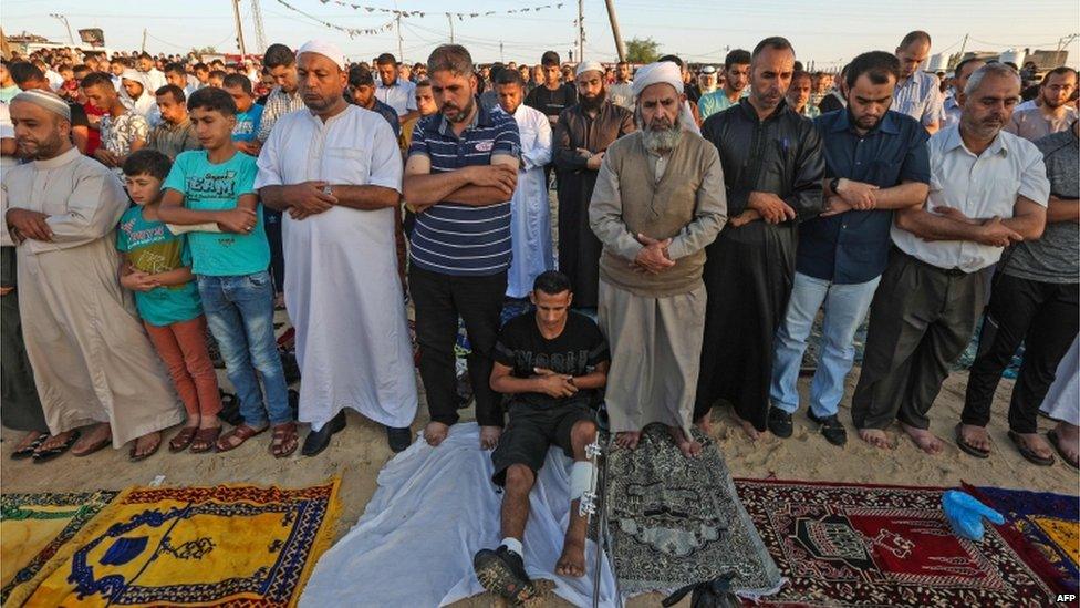 Palestinian faithful attend morning prayers during the first day of the celebrations of Eid al-Fitr, at the Israel-Gaza border east of Gaza city