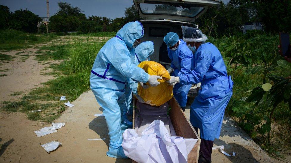 Health workers wearing protective suits as a precaution take the body of a covid-19 victim for burial at a graveyard. New Delhi