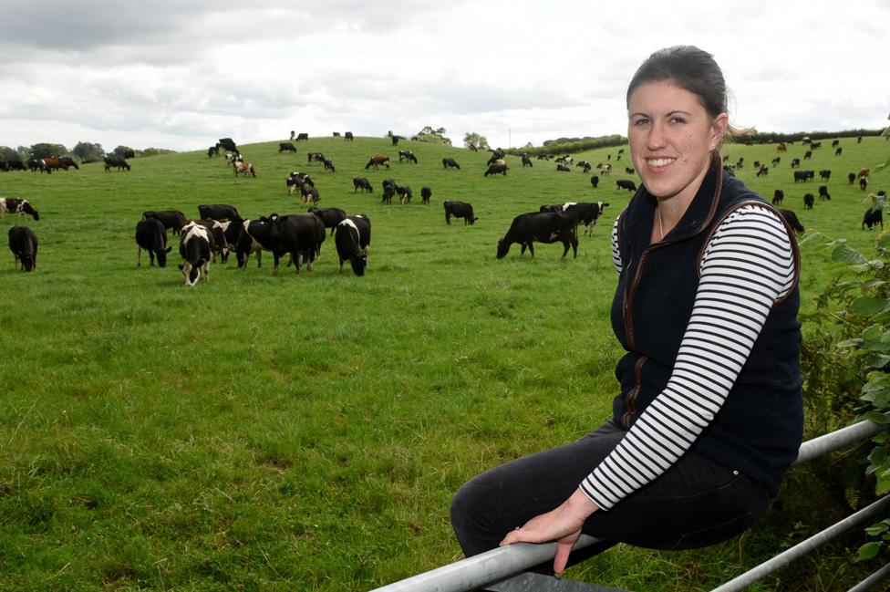 Liz Haines sits on a fence in front of a field