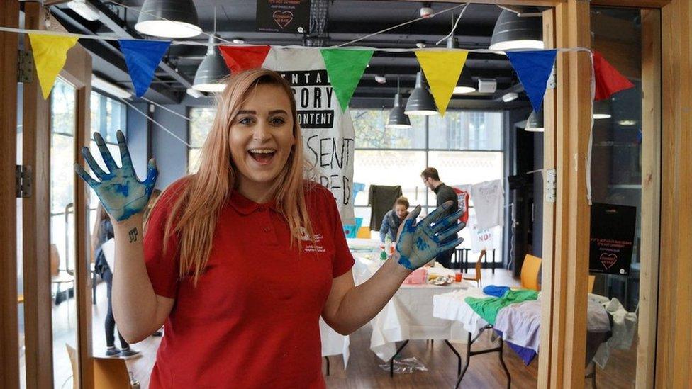 QUB Student officer holds hands in air smiling